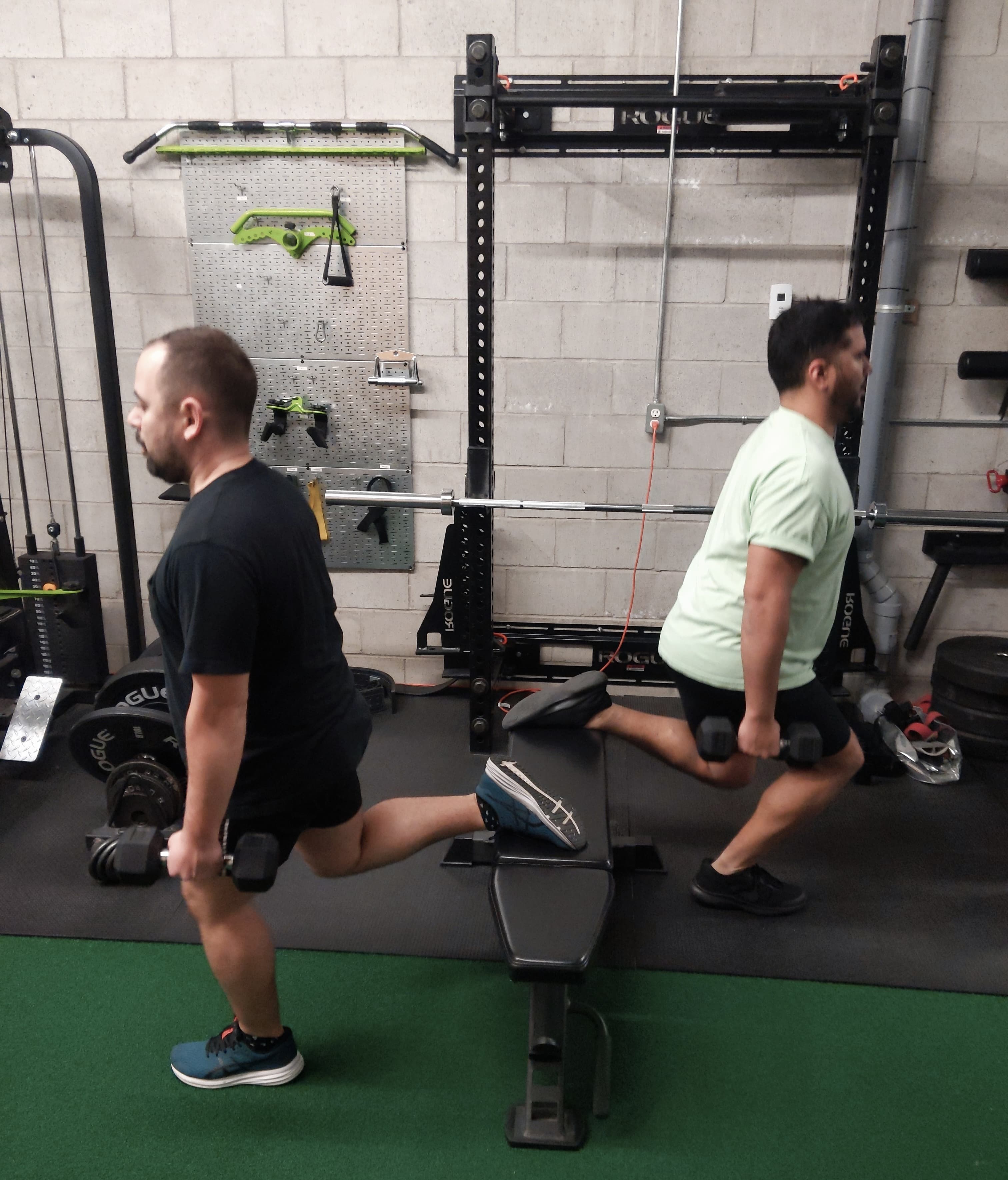 Two clients performing Bulgarian split squats with dumbbells at Carpio gym